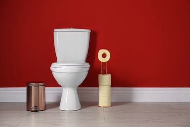 Photo of Toilet bowl with paper rolls and trash bin in restroom. Space for text