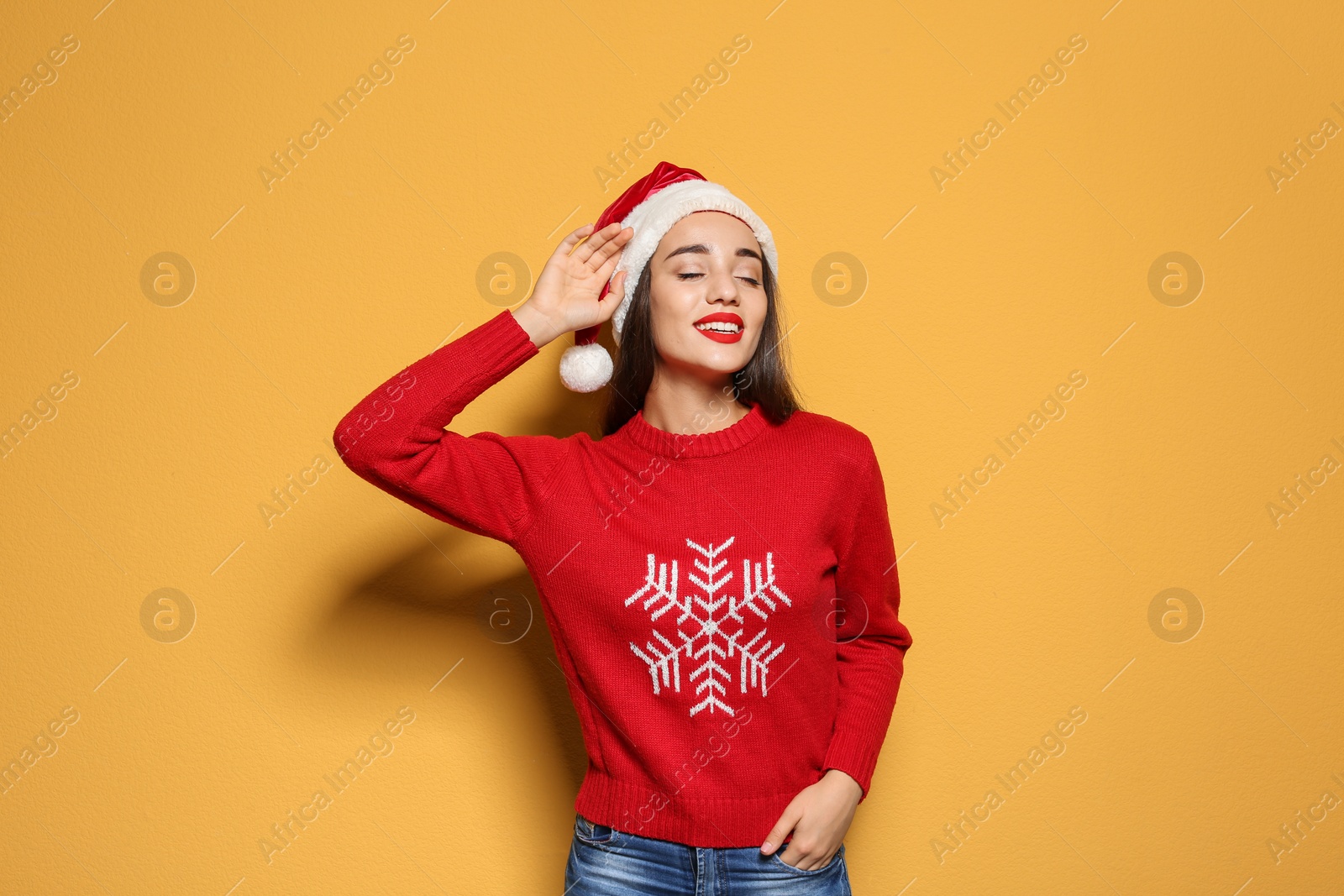 Photo of Young woman in Christmas sweater and hat on color background