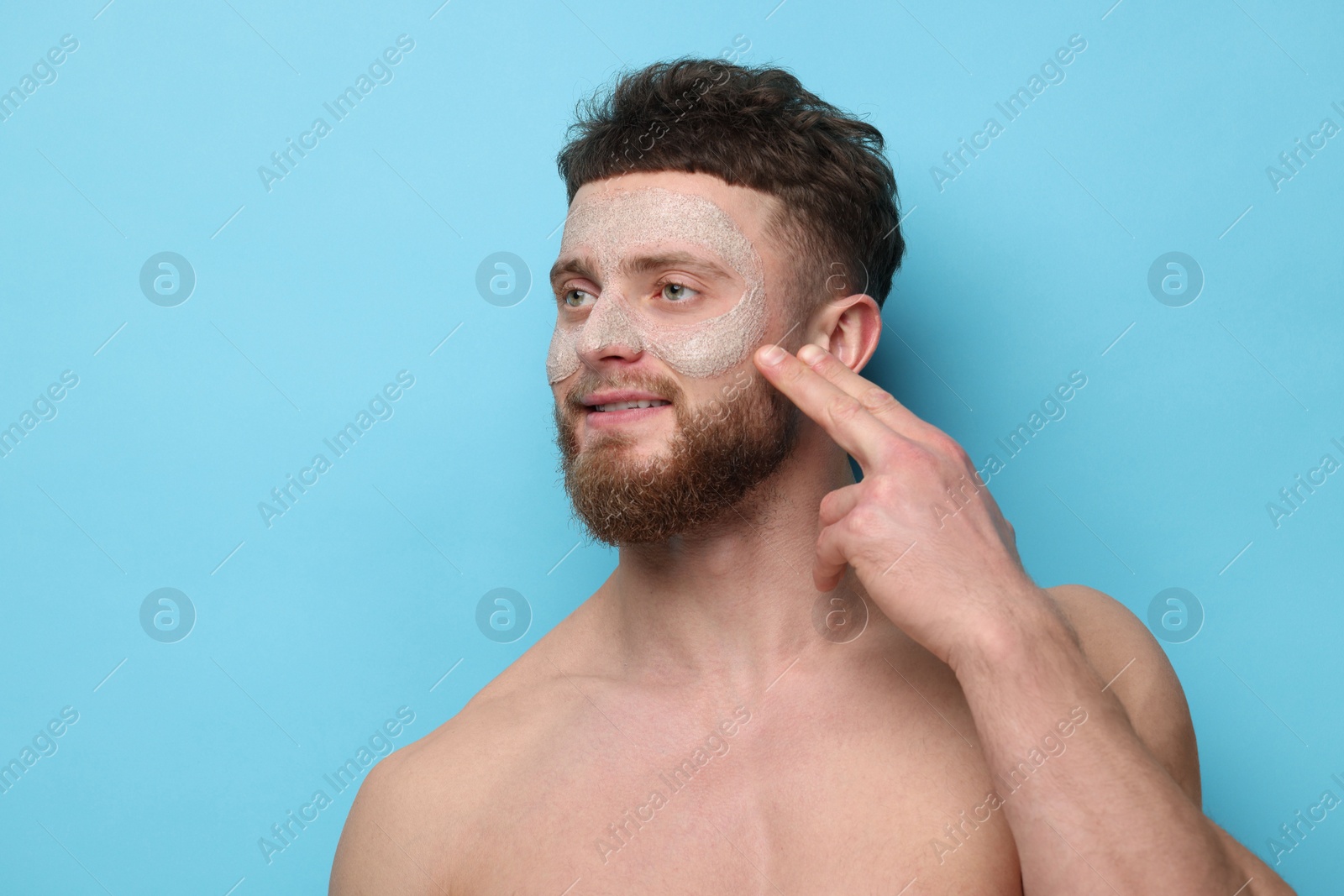 Photo of Handsome man with facial mask on his face against light blue background, space for text