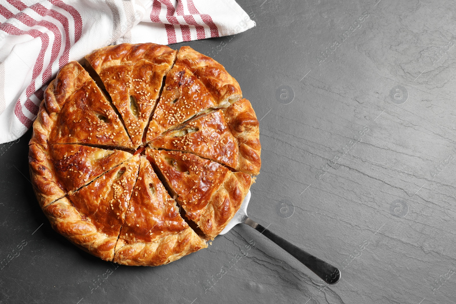 Photo of Cut delicious homemade pie and server on black table, top view