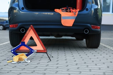 Photo of Emergency warning triangle and safety equipment near car, space for text