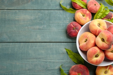 Photo of Fresh ripe donut peaches on light blue wooden table, flat lay. Space for text