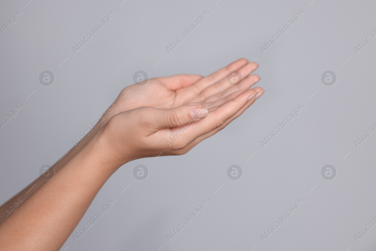 Photo of Woman stretching hands against light grey background, closeup. Space for text
