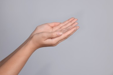 Woman stretching hands against light grey background, closeup. Space for text