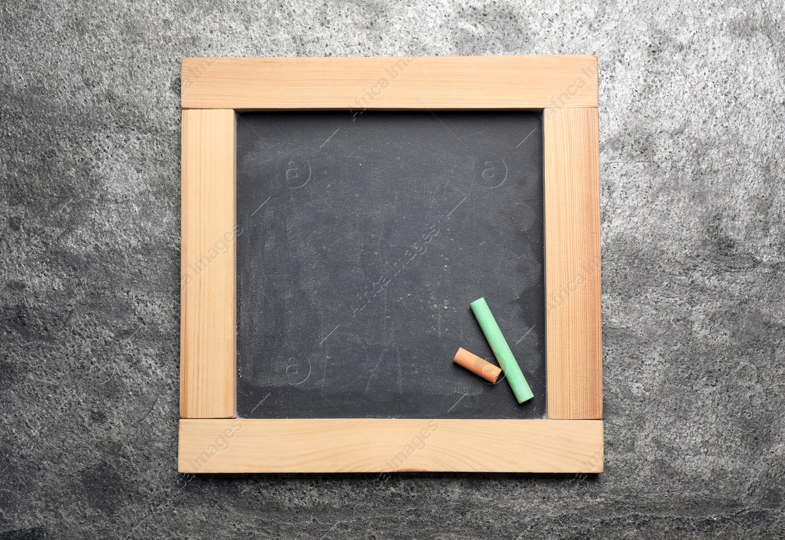 Photo of Empty blackboard with chalk on grey stone background, top view. Space for text