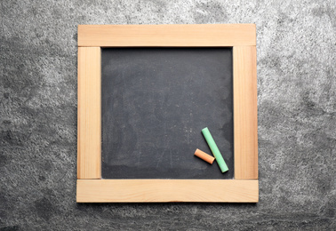 Photo of Empty blackboard with chalk on grey stone background, top view. Space for text