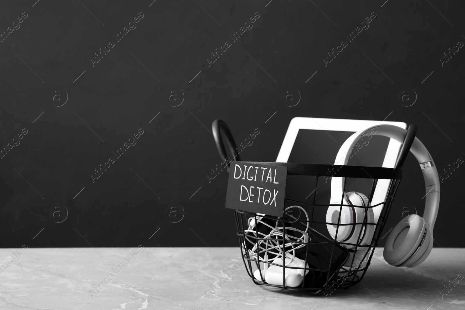 Photo of Trash bin with different gadgets and words DIGITAL DETOX on light grey marble table. Space for text