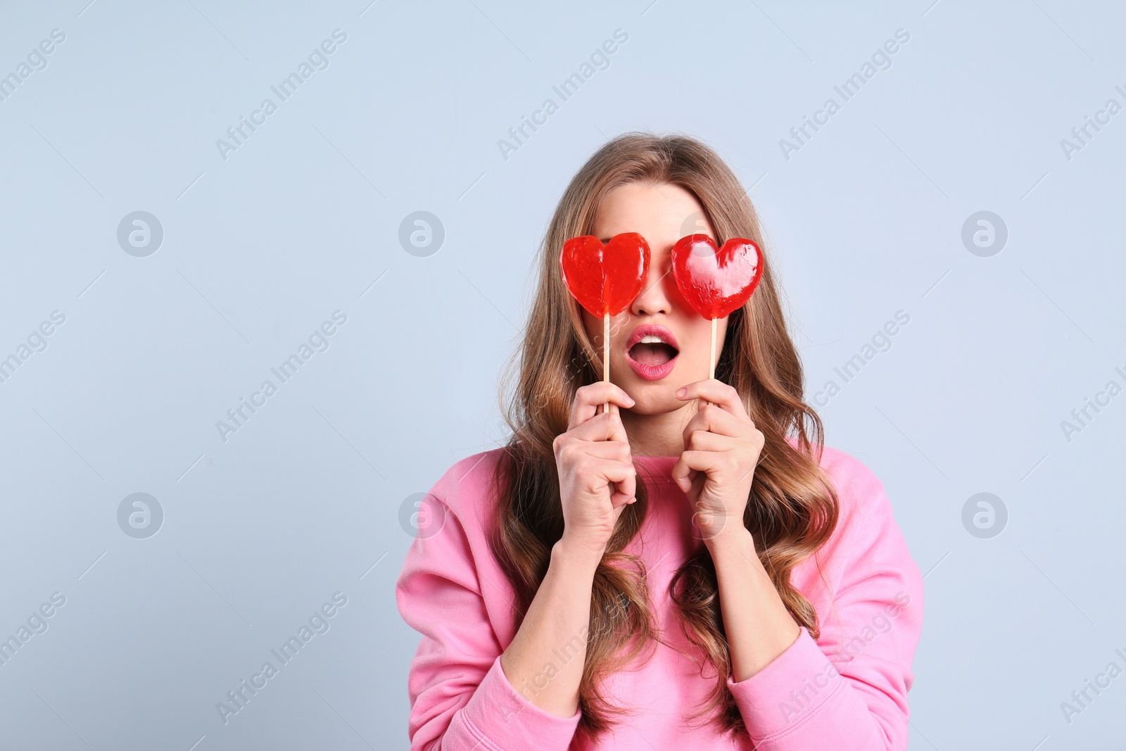 Photo of Portrait of young woman with long beautiful hair and lollipops on color background