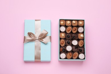 Photo of Open box of delicious chocolate candies on pink background, flat lay