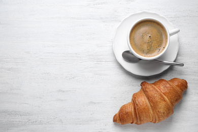 Photo of Tasty croissant and coffee on white wooden table, flat lay. Space for text