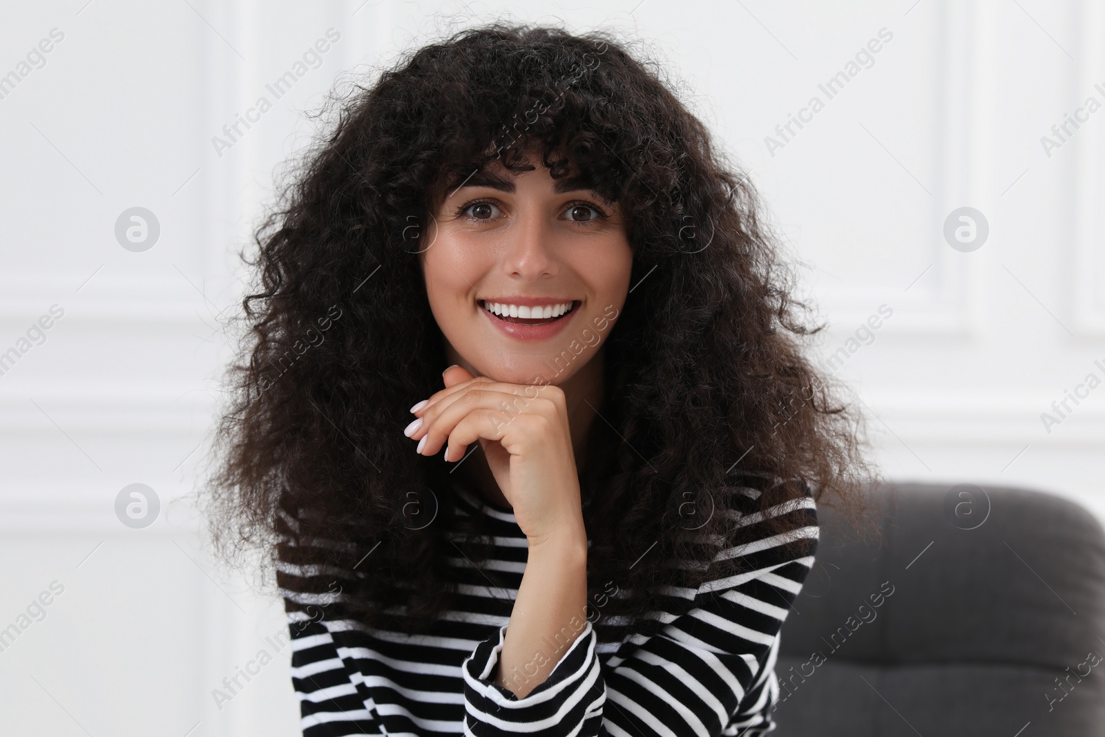 Photo of Portrait of beautiful woman with curly hair indoors. Attractive lady smiling and looking at camera