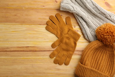 Photo of Stylish gloves, hat and scarf on wooden background, flat lay. Space for text