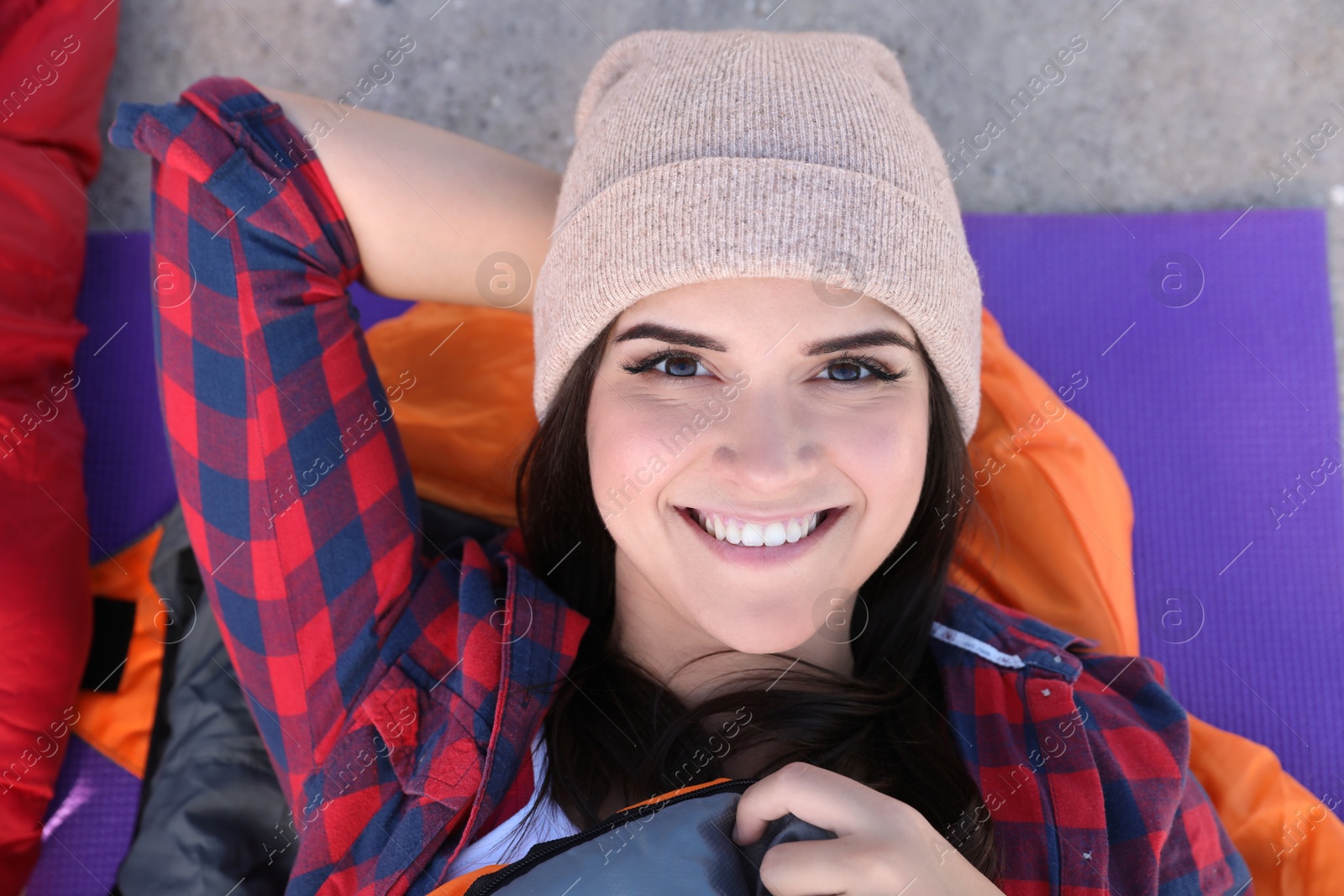 Photo of Female camper lying in sleeping bag on mat, top view