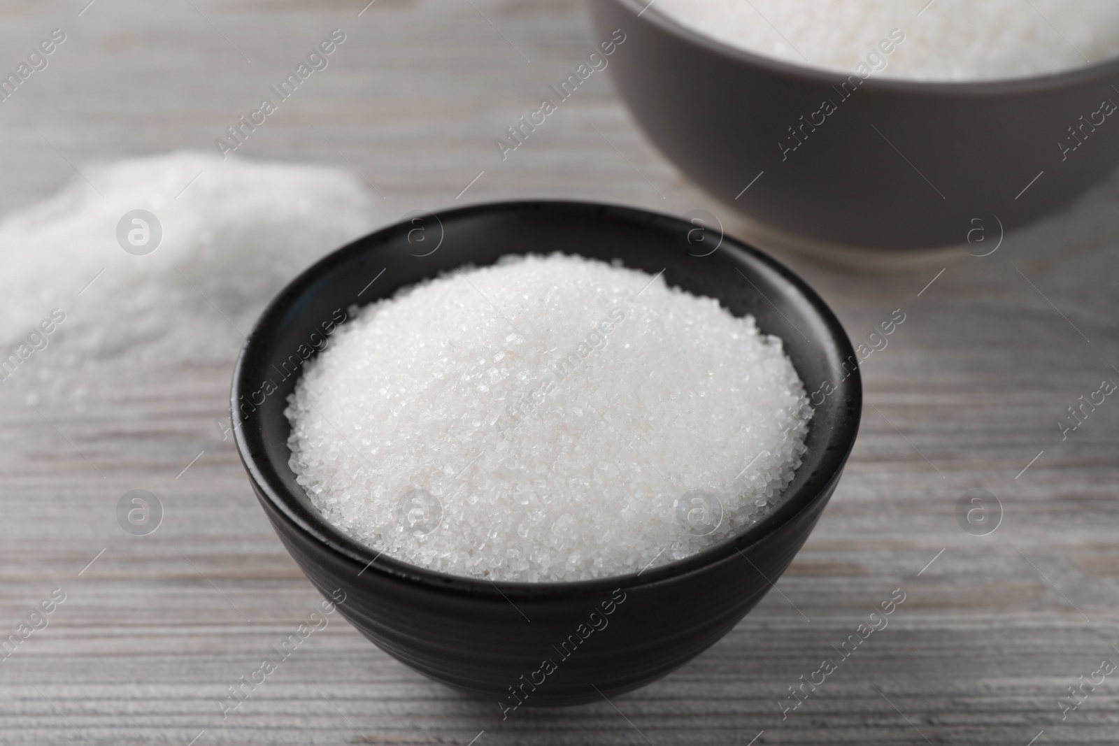 Photo of Granulated sugar on light wooden table, closeup