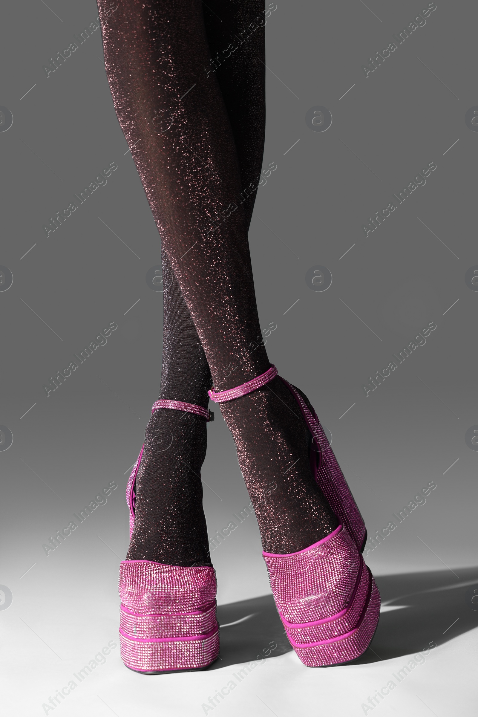 Photo of Woman wearing pink high heeled shoes with platform and square toes on light grey background, closeup