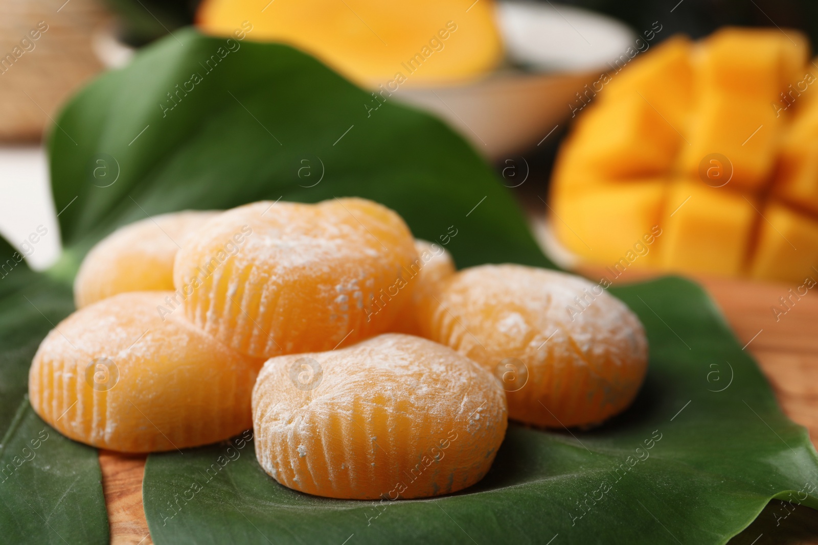 Photo of Delicious mochi with green leaf on wooden board, closeup. Traditional Japanese dessert