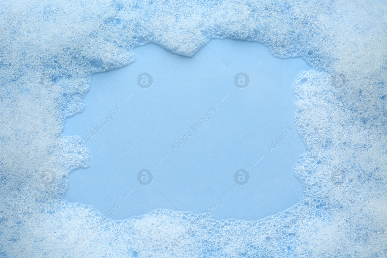 Photo of Frame of fluffy bath foam on light blue background, top view. Space for text