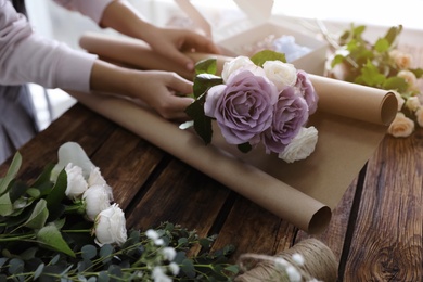 Photo of Florist making beautiful wedding bouquet at wooden table, closeup