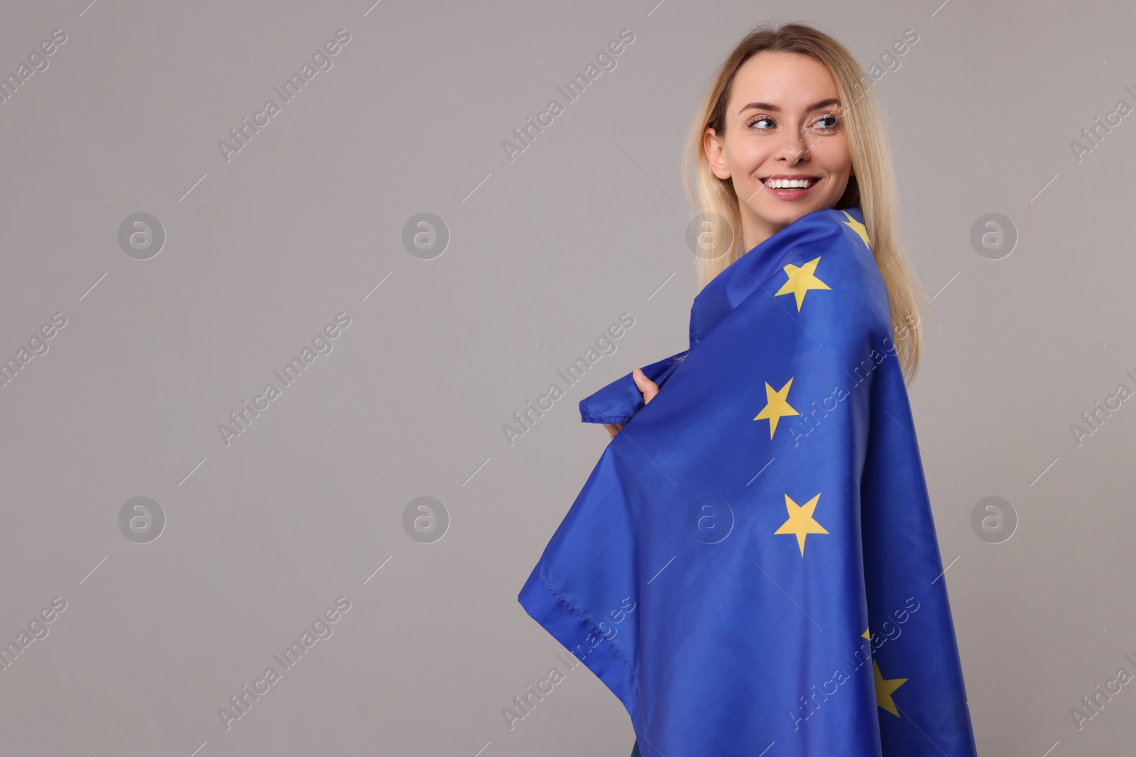 Photo of Happy woman with flag of European Union on grey background, space for text