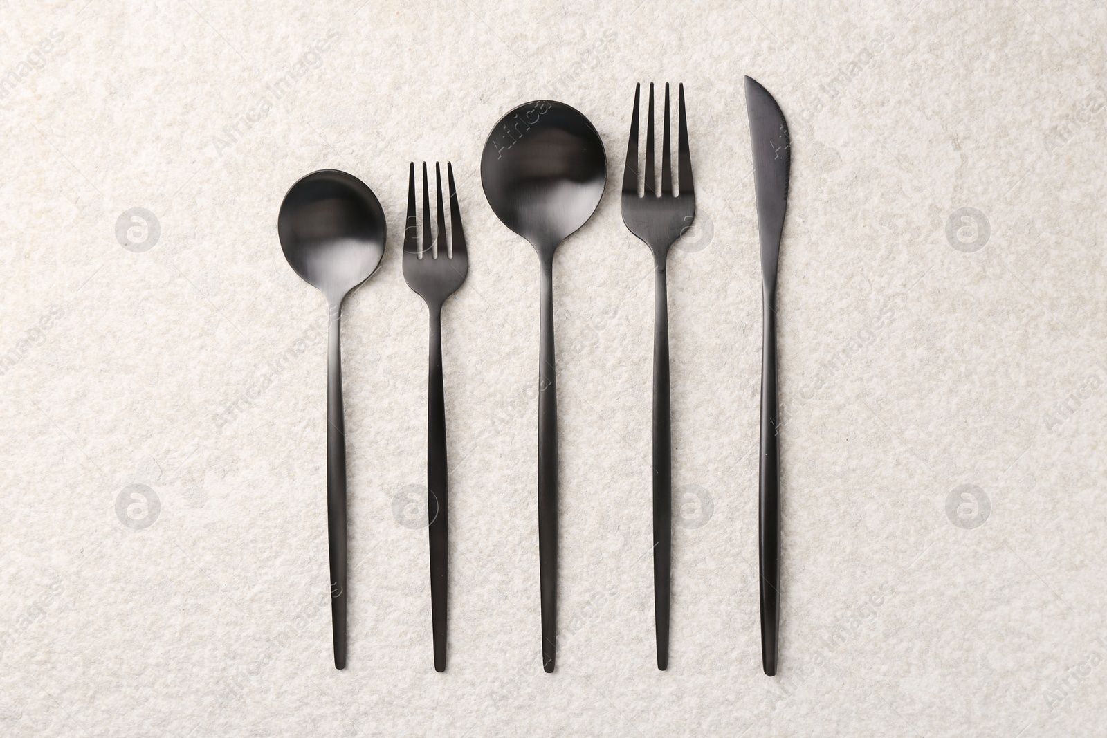 Photo of Stylish cutlery set on beige textured table, flat lay