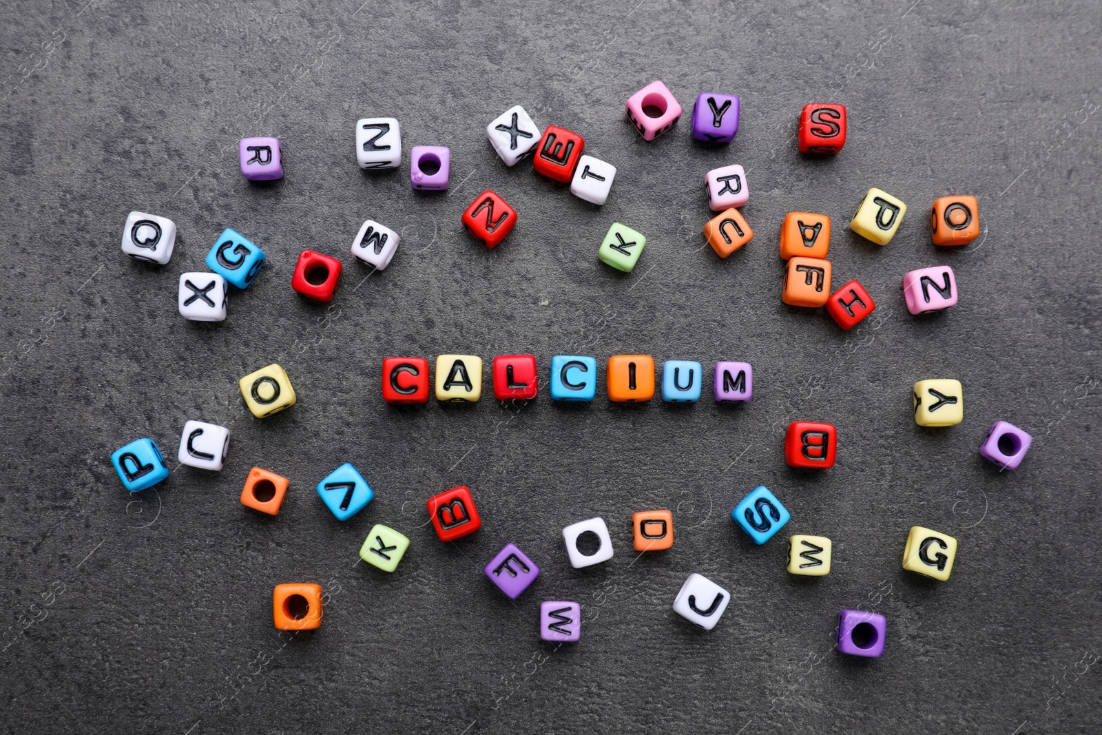 Photo of Word Calcium made of colorful plastic beads with letters on black background, top view