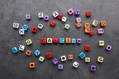 Photo of Word Calcium made of colorful plastic beads with letters on black background, top view