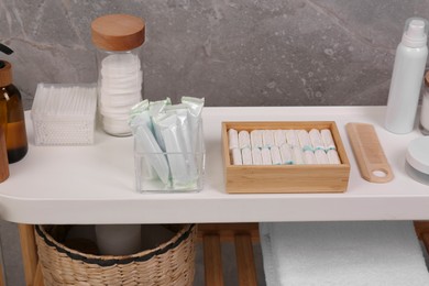 Photo of Many different tampons and personal care products on white table near grey wall
