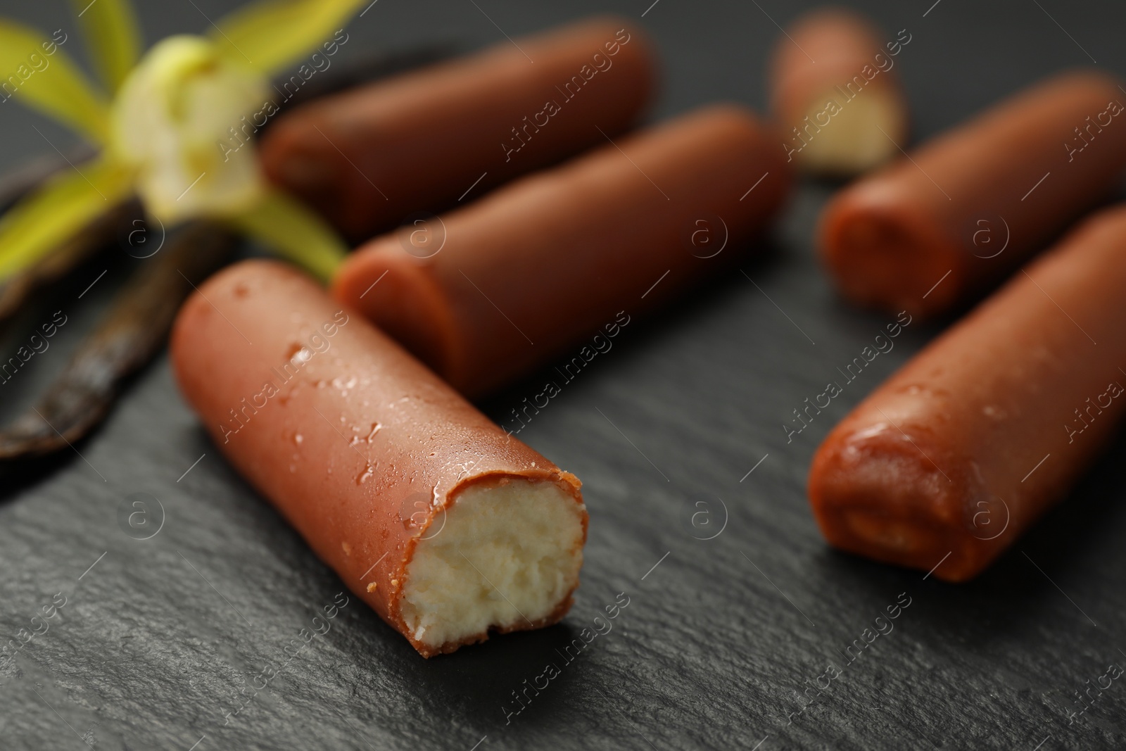 Photo of Glazed curd cheese bars on black table, closeup