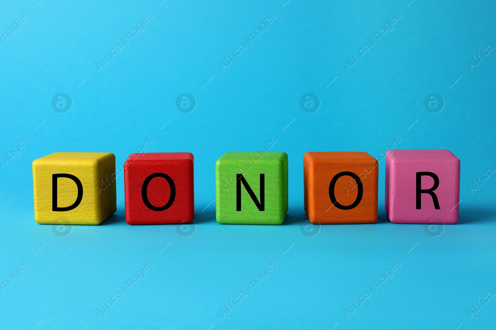 Photo of Word Donor made of colorful wooden cubes on light blue background