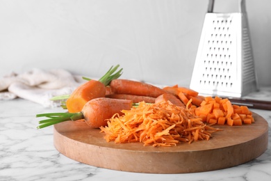 Photo of Board with differently cut carrots on marble table