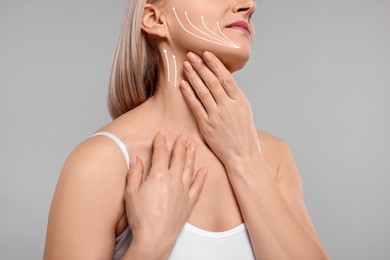 Woman with perfect skin after cosmetic treatment on grey background, closeup. Lifting arrows on her neck and face