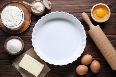 Making shortcrust pastry. Baking dish, rolling pin and different ingredients for dough on wooden table, flat lay