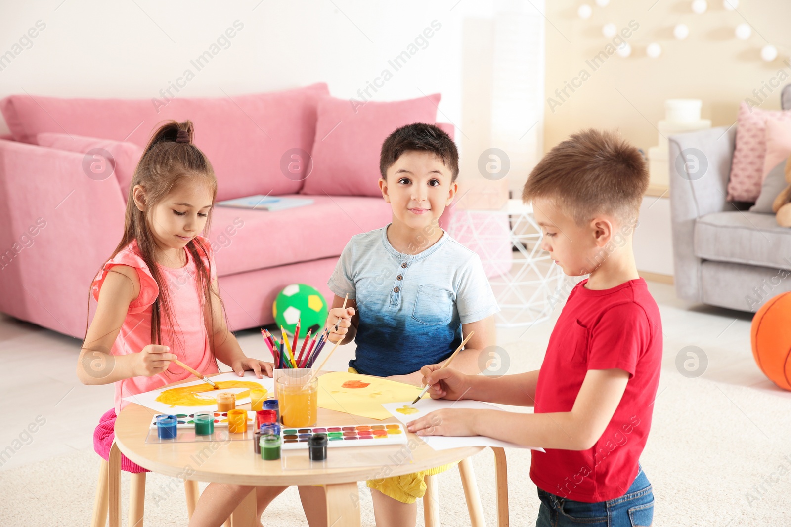 Photo of Cute little children painting at table in playing room