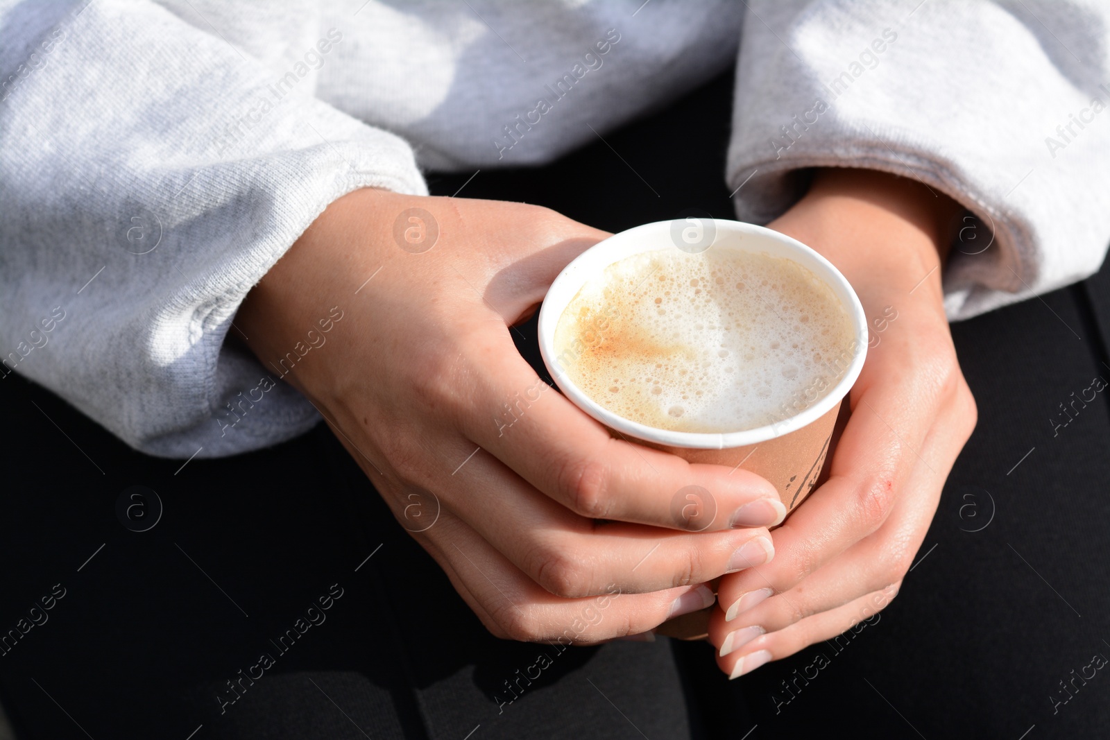 Photo of Woman sitting with cardboard cup of coffee, closeup