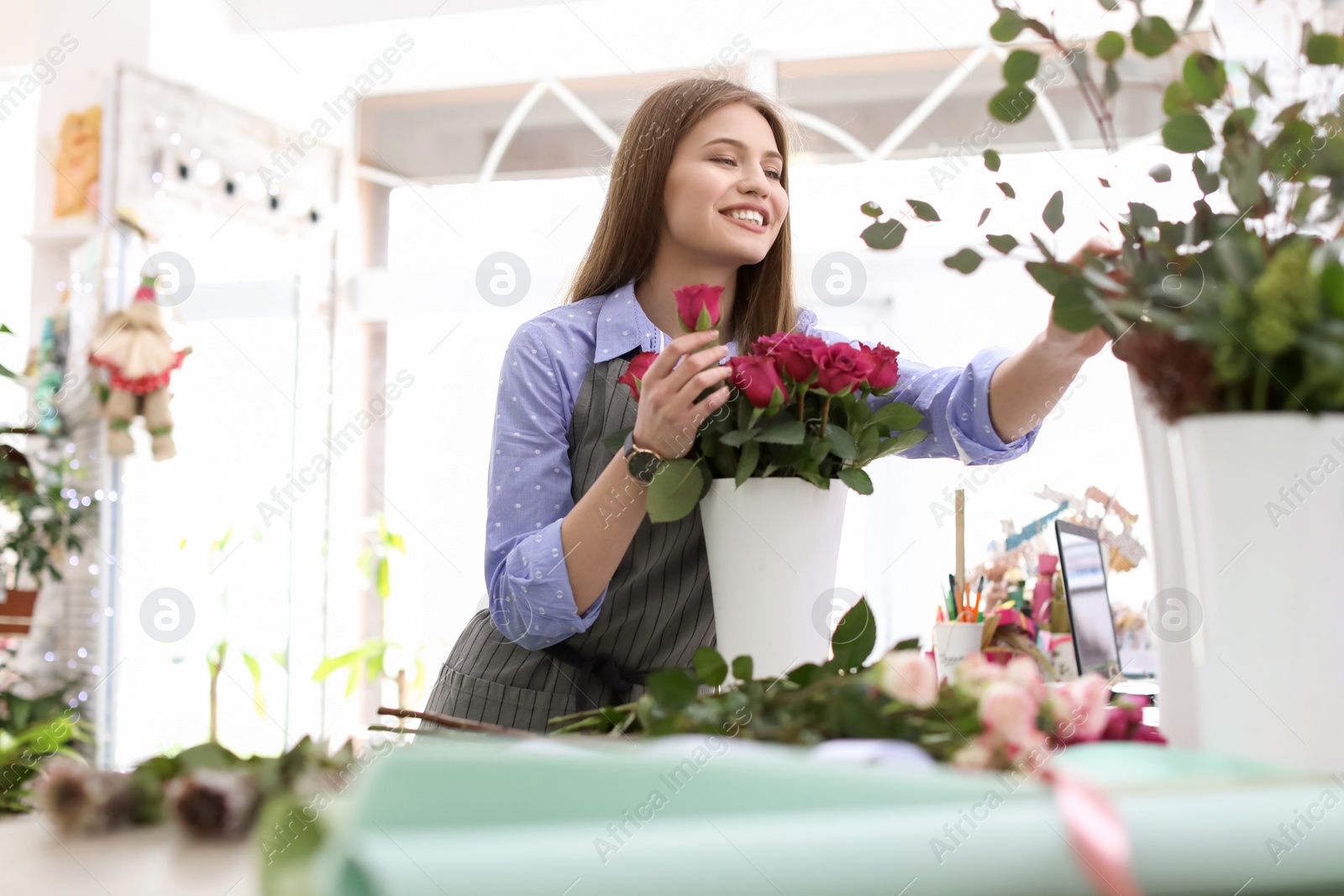 Photo of Female florist making beautiful bouquet in flower shop