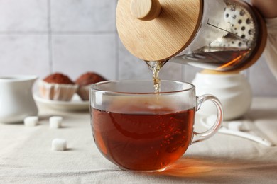 Photo of Pouring warm tea into cup on light table, closeup