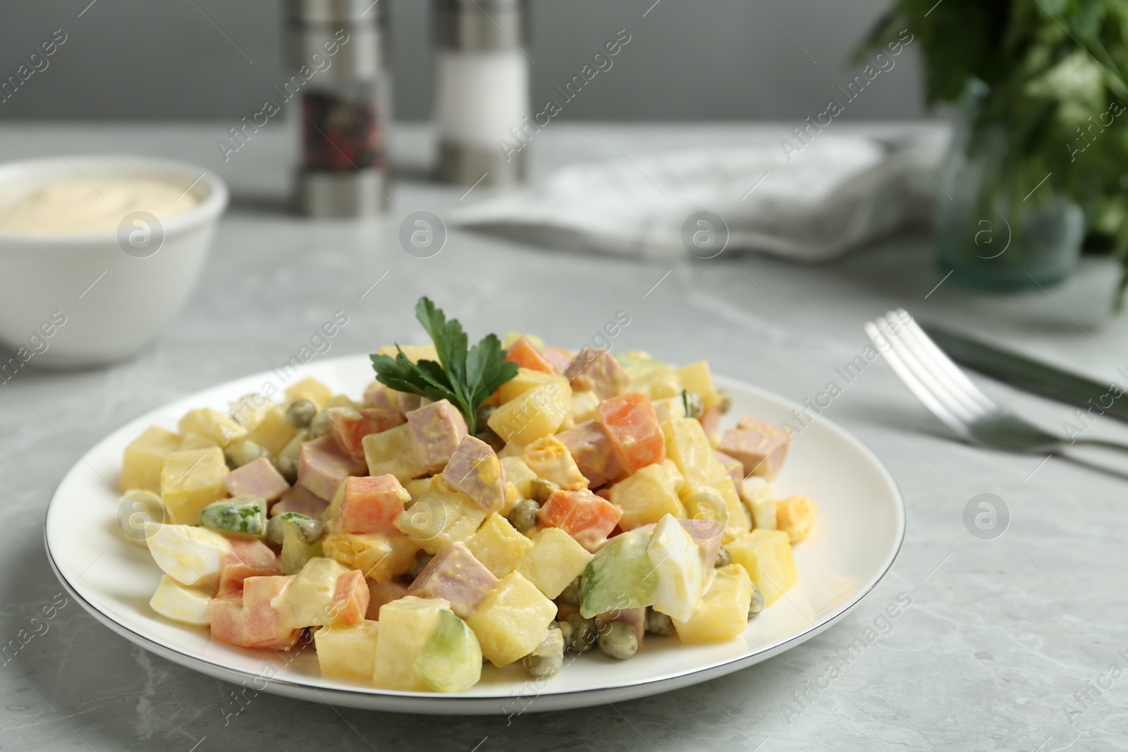 Photo of Delicious russian salad Olivier served on light grey marble table