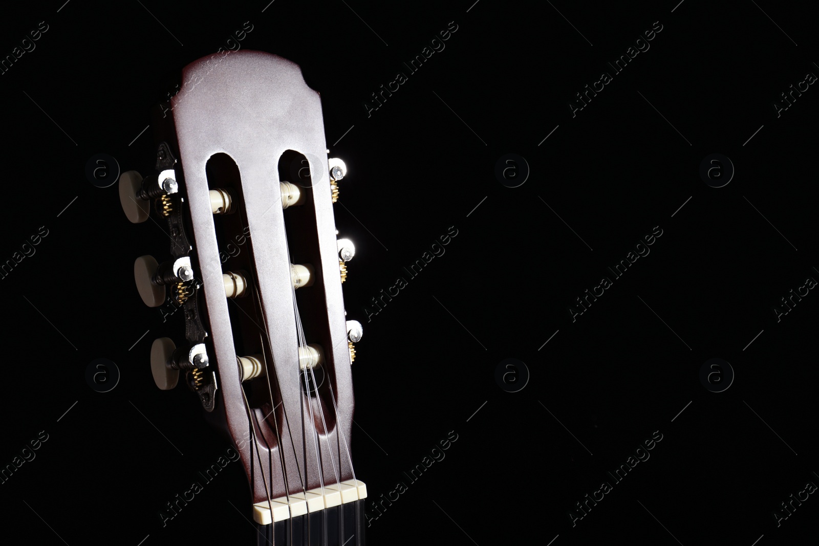 Photo of Head of acoustic guitar in darkness, closeup. Space for text
