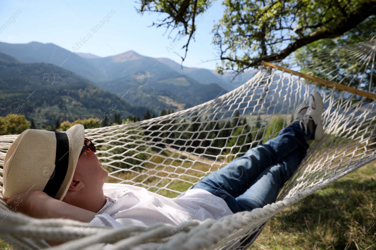 Photo of Young man resting in hammock outdoors on sunny day