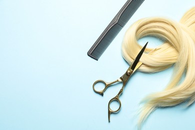 Photo of Professional hairdresser scissors and comb with blonde hair strand on light blue background, flat lay. Space for text