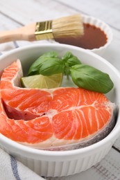 Fresh marinated fish, brush and lime on white wooden table, closeup