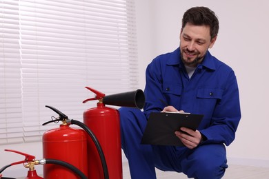 Man with clipboard checking fire extinguishers indoors