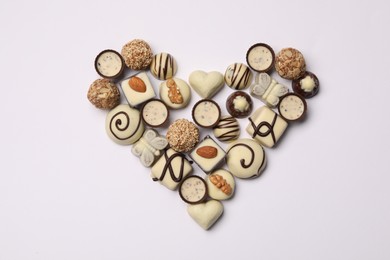 Photo of Heart made with delicious chocolate candies on white background, top view