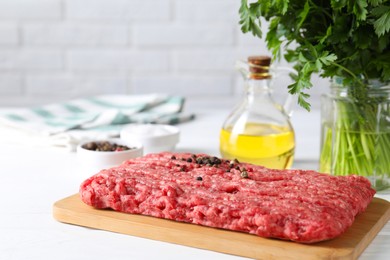 Raw ground meat, spices, oil and parsley on white table