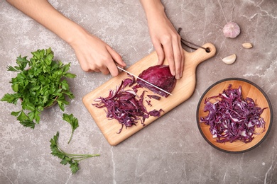 Photo of Woman cutting red cabbage on wooden board, top view