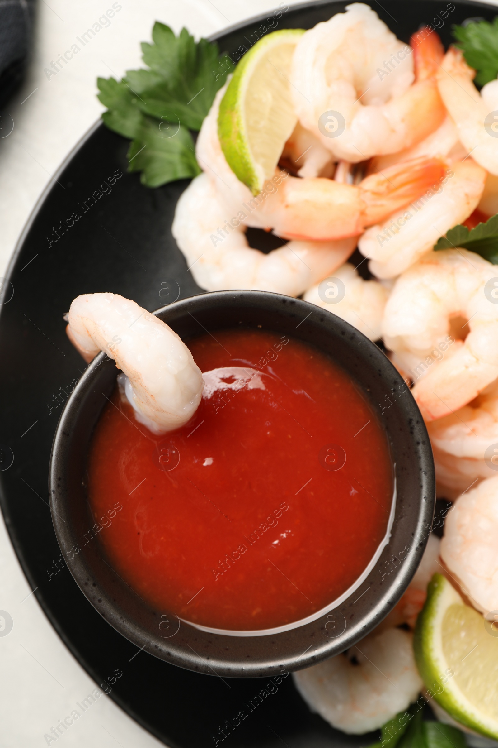 Photo of Tasty boiled shrimps with cocktail sauce, parsley and lime on light grey table, top view