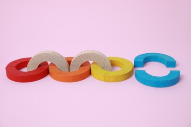 Photo of Colorful wooden pieces of playing set on pink background. Educational toy for motor skills development