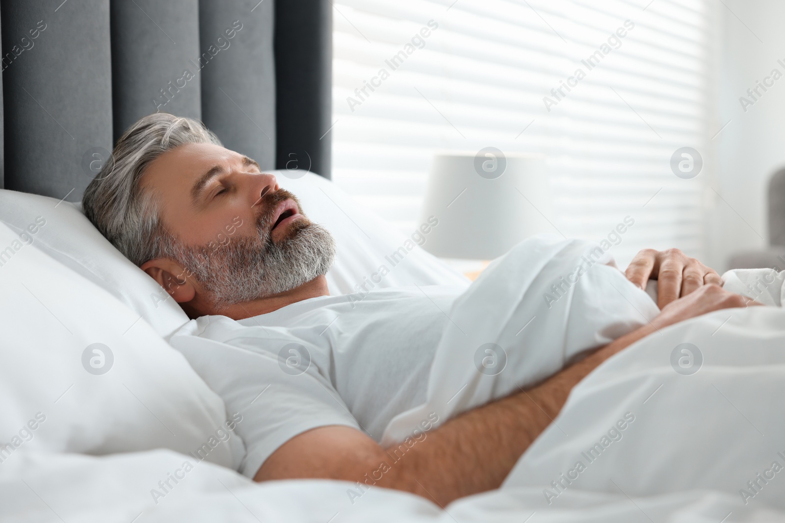 Photo of Man snoring while sleeping in bed at home