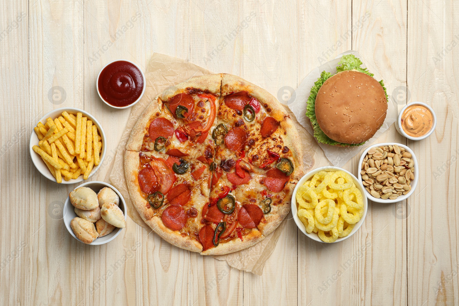 Photo of Pizza, onion rings and other fast food on wooden table, flat lay