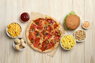 Photo of Pizza, onion rings and other fast food on wooden table, flat lay